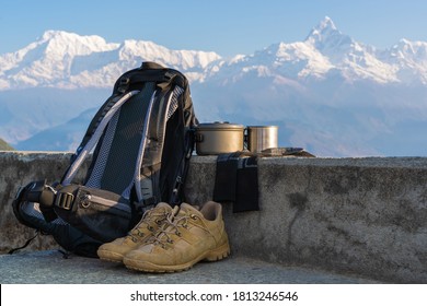 Trecking Or Hiking Equipment Set With Annapurna Mountain Range On Background. Bagpack, Hiking Shoes, Socks, Metal Cup, And Kettle Pot. Outdoor Activity Concept.