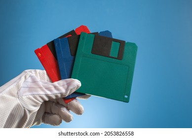 Tree Blank Floppy Disc Of Multicolor In Hand, On A Blue Background. Outdated Retro Digital Media. Old Computer Technology.