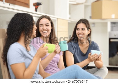 Tree happy roommates drinking and talking in the kitchen reforming house