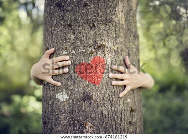 Tree hugging, little boy giving a tree a hug\
with red heart concept for love\
nature