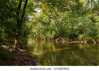 The tree lined banks of the Shenandoah River on a hot summer day. - Shutterstock ID 1172837833