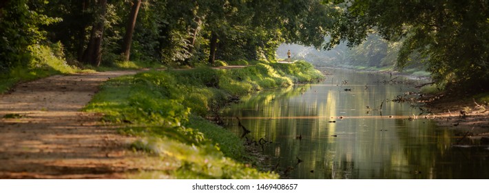 Tree Lined Serene Walking and Jogging Path in the Morning with Dappled Sun Light and a Calm River at Great Falls Park in Maryland USA