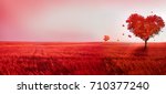 Tree of love. Red heart shaped tree at sunset. Beautiful landscape with red tree and falling leaves.Love background