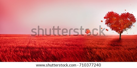 Tree of love. Red heart shaped tree at sunset. Beautiful landscape with red tree and falling leaves.Love background