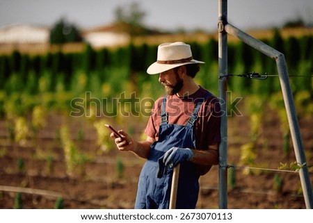 Tree nursery worker using mobile phone while working in a field. Copy space. 