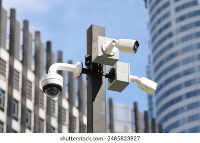 Tree security cameras on pole with building in background.