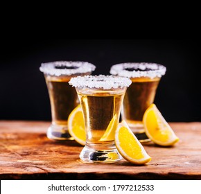 Tree Shot Glasses Of Mexican Tequila Cocktail With Lemon Slices And Salt On Wooden Table With Black Background. Shooter Drink On Bar Counter For Happy Hour Menu Design Banner.