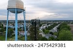 Tree Style Cell Tower Next To A Water Tower In A Neighborhood Setting