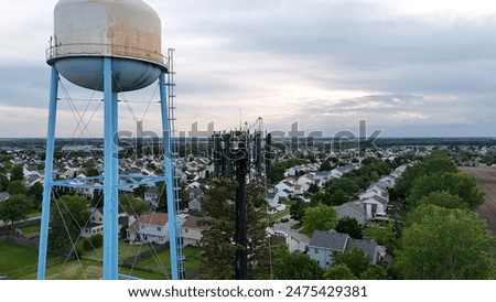 Tree Style Cell Tower Next To A Water Tower In A Neighborhood Setting