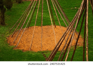 Tree trunks tied together as scaffolding for a teepee in autumn