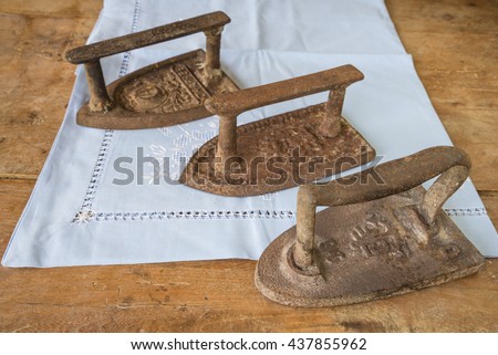 Tree vintage clothes irons on a white napkin and on a wooden background