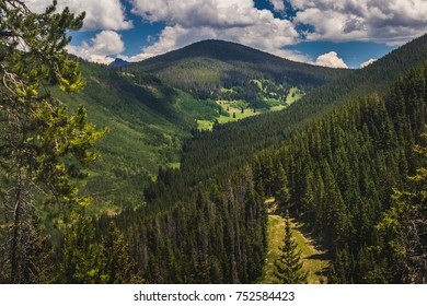 Tree-covered Vail Mountain With Blue Skies And Shadows Cast From The Clouds Above On A Summer Day In Vail, Colorado