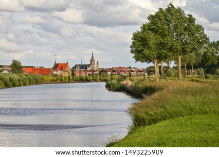 Trees along the river IJzer with the church of Diksmuide in the background. In Flanders Fields. Belgium.