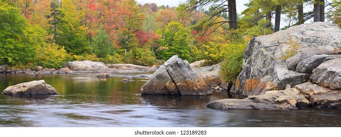 Trees and rocks on an island reflected in a Moose River in the Adirondack Mountains of New York (Panorama)