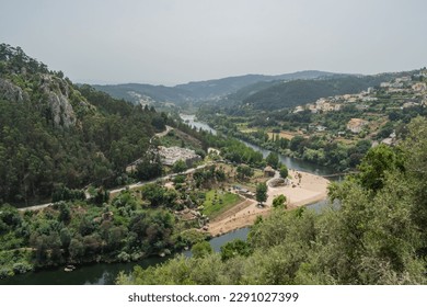 Treetops with leaves on the bank of the Mondego with aerial and panoramic view of the river beach of Reconquinho, Penacova PORTUGAL