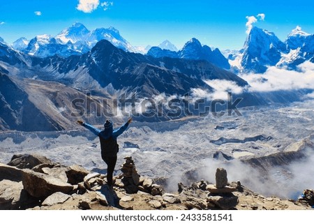 A Trekker celebrates reaching the summit of 5350 m high Gokyo Ri providing grand stand views of the Highest mountain peaks on Earth - Everest,Lhotse,Makalu, Cho Oyu and the Ngozumpa glacier in Nepal