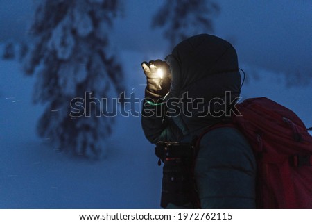 Trekker with a headlamp walking in a snowy Riisitunturi National Park, Finland
