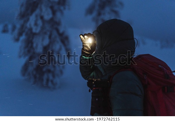 Trekker with a headlamp walking in a snowy\
Riisitunturi National Park,\
Finland