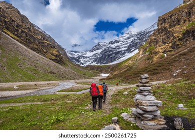 Trekkers with backpack traversing Rupin pass trail, It is full of diversity from majestic Himalayan ranges to waterfalls, glacial meadows, snow-covered landscape, lush forests. - Powered by Shutterstock