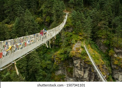 Trekkers And Sherpa Crossing A Suspension Bridge In Everest Base Camp Route At (Sagarmatha National Park - Himalaya), Nepal.