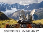 Trekking boots with insoles and socks dry on the background of a mountain valley. Boots in focus, background blurred.