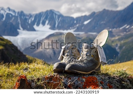Trekking boots with insoles and socks dry on the background of a mountain valley. Boots in focus, background blurred.