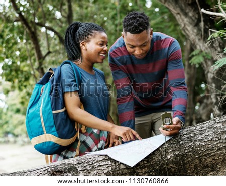 Trekking couple using map and compass in a forest