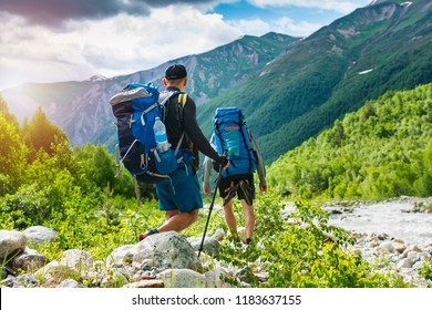 Trekking in mountains. Mountain hiking. Tourists with backpacks hike on rocky way near river. Wild nature with beautiful views. Sport tourism in Svaneti, Georgia. Hikers and climbers in mounts - Shutterstock ID 1183637155