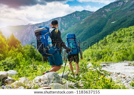 Trekking in mountains. Mountain hiking. Tourists with backpacks hike on rocky way near river. Wild nature with beautiful views. Sport tourism in Svaneti, Georgia. Hikers and climbers in mounts