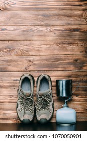 Trekking Shoes, Camping Gas Bottle -equipment For Outdoor Activities On A Wooden Background. Eqipment For Making Tea And Cofee On A Gas During The Journey