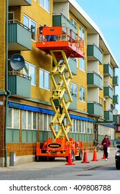 Trelleborg, Sweden - April 12, 2016: Workers On Top Of A Riwal Scissor Lift Platform Performing Some Window Repairs Outside An Apartment.