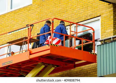 Trelleborg, Sweden - April 12, 2016: Workers On Top Of A Riwal Scissor Lift Platform Performing Some Window Repairs Outside An Apartment.