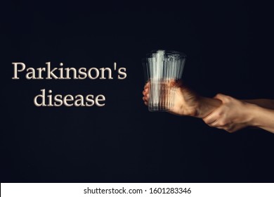 Trembling hands with glass of water and text PARKINSON'S DISEASE on dark background