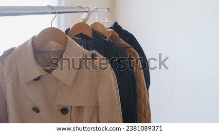 Trench coat hanging on a hanger.