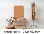 Trench coat on hanger, bench and shoes near white brick wall in room