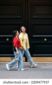 Trendy asian female friends talking while walking in the city. - Shutterstock ID 2209477937