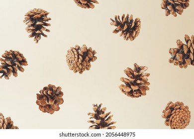 Trendy autumn composition with flying pinecones agains cream background. Creative fall wallpaper.