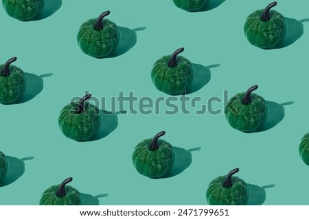Trendy autumn or fall pattern made with green pumpkins on green background. Minimal autumn composition. Nature flat lay. Season concept. Pumpkin aesthetic.