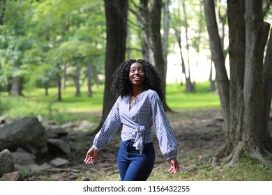 Trendy Black Woman With Curls Looking Up In Green Park With Feeling Of Great Excitement 