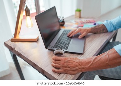 Trendy businessman drinking a coffee at breakfast time while working  - Senior entrepreneur working with laptop - Drink trends and hipster workers concept - Focus on left hand. - Powered by Shutterstock