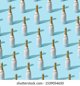 Trendy Christmas pattern made with white champagne bottle on bright light blue background. Minimal Christmas party concept.