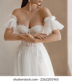 Trendy classic wedding dress with cleavage and wide short sleeves decorated with floral lace. Bride in the shoulderless white wedding dress with deep neckline and fancy sleeves