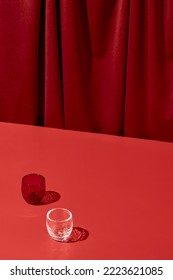 Trendy coloured background with textile. Red background with red table and drapery textile with shadows from glass. Aesthetic red backdrop. Minimal composition with empty place on red background - Shutterstock ID 2223621085