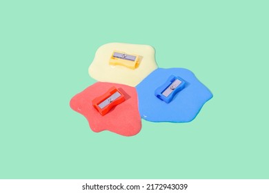 Trendy Composition With Colorful Pencil Sharpeners Dipped In Liquid On Olive Green Background. Surreal Office Or School Idea.