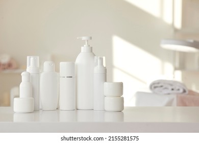 Trendy Cosmetic Products Of New Female Skin Care Line For Health, Beauty And Wellbeing. White Mockup Bodycare Bottles, Jars And Soap Dispenser With Pump Lid Standing In Row On Shelf Or Table In Salon