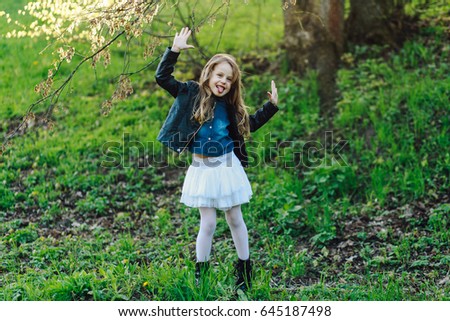 Trendy cute little girl in stylish clothes having fun outdoors in the springtime