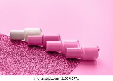 Trendy design template with nail polish glass bottles on pink and sparkling background. Manicure concept. Mockup for your design with copy space.