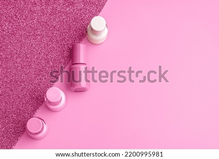 Trendy design template with nail polish glass bottles on pink and sparkling background. Manicure concept. Mockup for your design with copy space. Flat lay style.