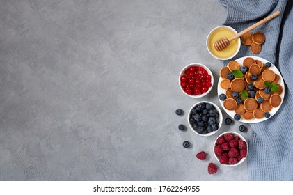 Trendy dessert and healthy breakfast. Pancake Cereal or Mini Pancakes with honey, fresh berries on slate background top view. Space for your text - Shutterstock ID 1762264955