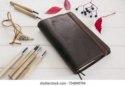 Trendy and Elegant mock up for visualization for private business. Vintage leather notepad, red leaves of grapes,celtic amulet for luck and craftsman tools on a white background black vintage table.